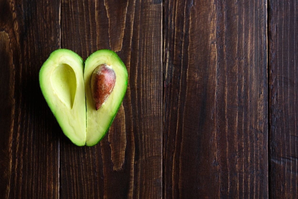 A cut in half avocado sitting on top of a wooden table.