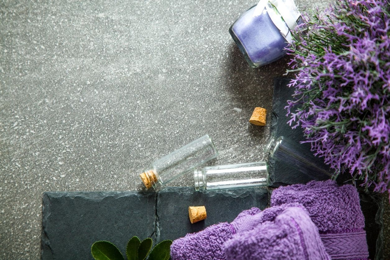 A couple of bottles and some purple towels on the ground.